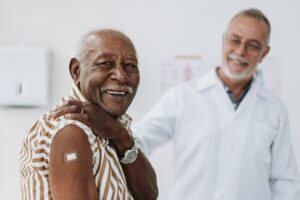 Senior man bandaging vaccine on arm